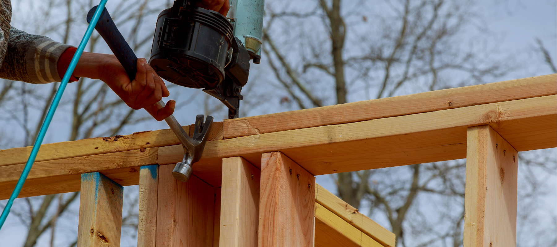 Individual building a deck with a nail gun and hammer